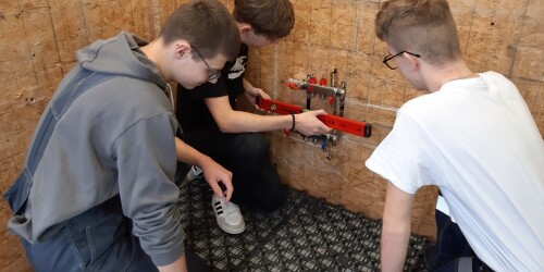 Uczniowie instalują rozdzielacz do ogrzewania podłogowego