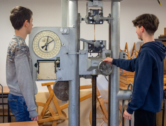 Uczniowie obsługujący maszynę do badania twardości drewna
