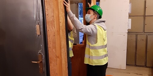 Uczeń trzymający futrynę drzwiową przy montażu