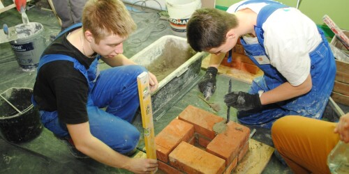 Uczniowie budują komin spalinowy z cegły
