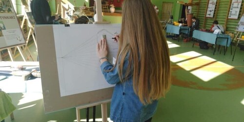 Uczennica malująca portret odwrócona tyłem do obiektywu