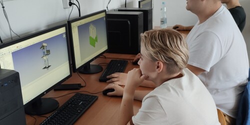 Uczennica i uczeń projektujący przy komputerze wydruki 3D