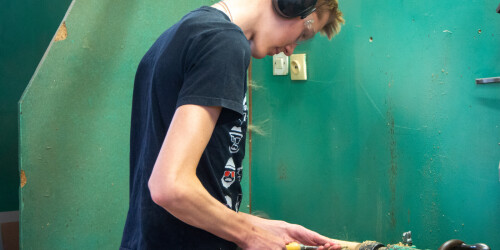 Uczeń obrawiający drewno na maszynie