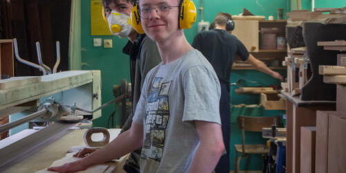 Uśmiechnięty uczeń na tle maszyny do obróbki drewna