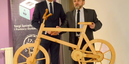 Instruktor zawodu trzymajacy rower wykonany z drewna a obok prezydent Miasta Lublin Krzysztof Żuk
