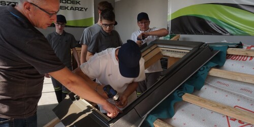 Uczniowie uczą się od instruktora jak układać dachówkę