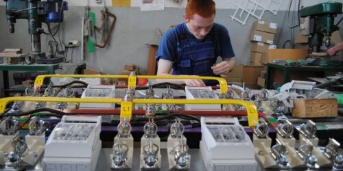Uczeń montuje aparaty elektryczne w rozdzielnicy u swojego pracodawcy